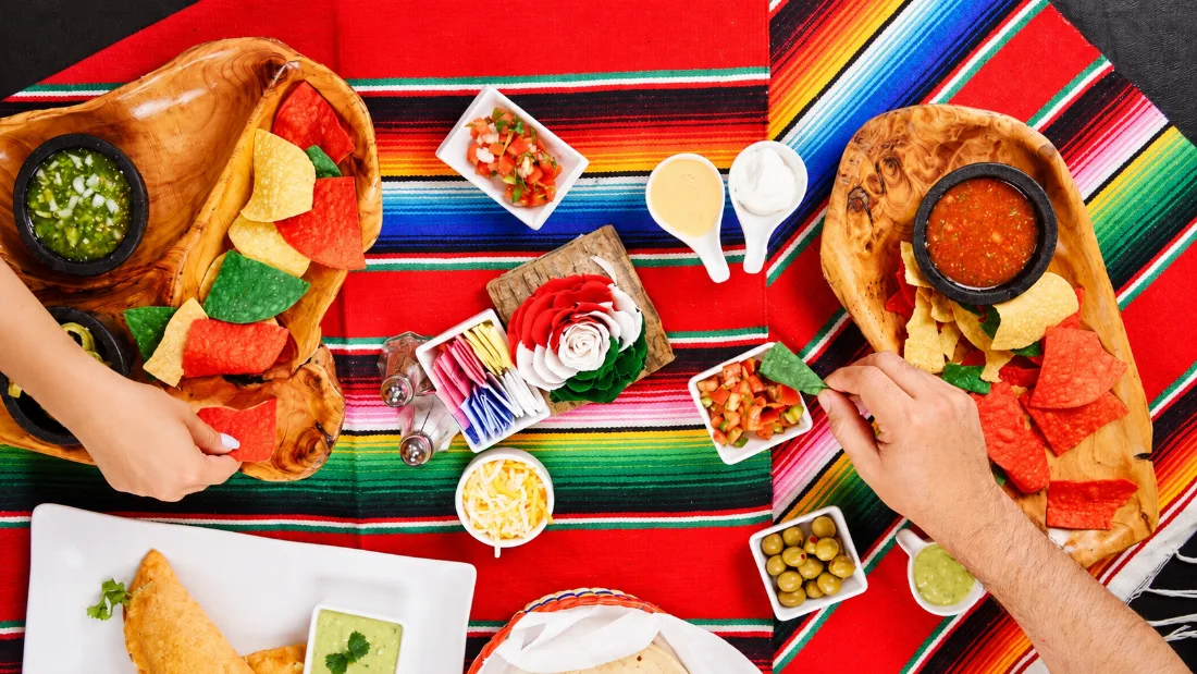 Hands sharing Mexican food around a colorful table